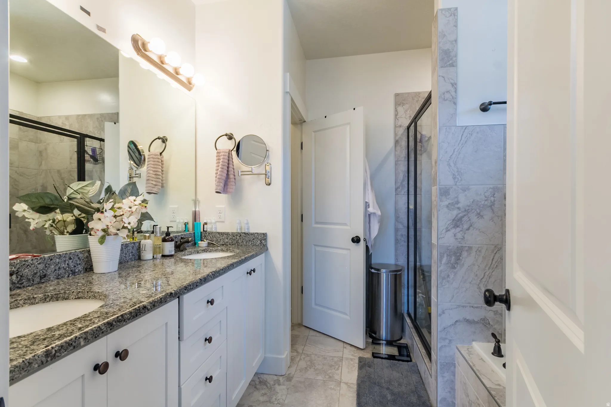 Dual vanity with stone countertop, undermount sinks, and white cabinetry