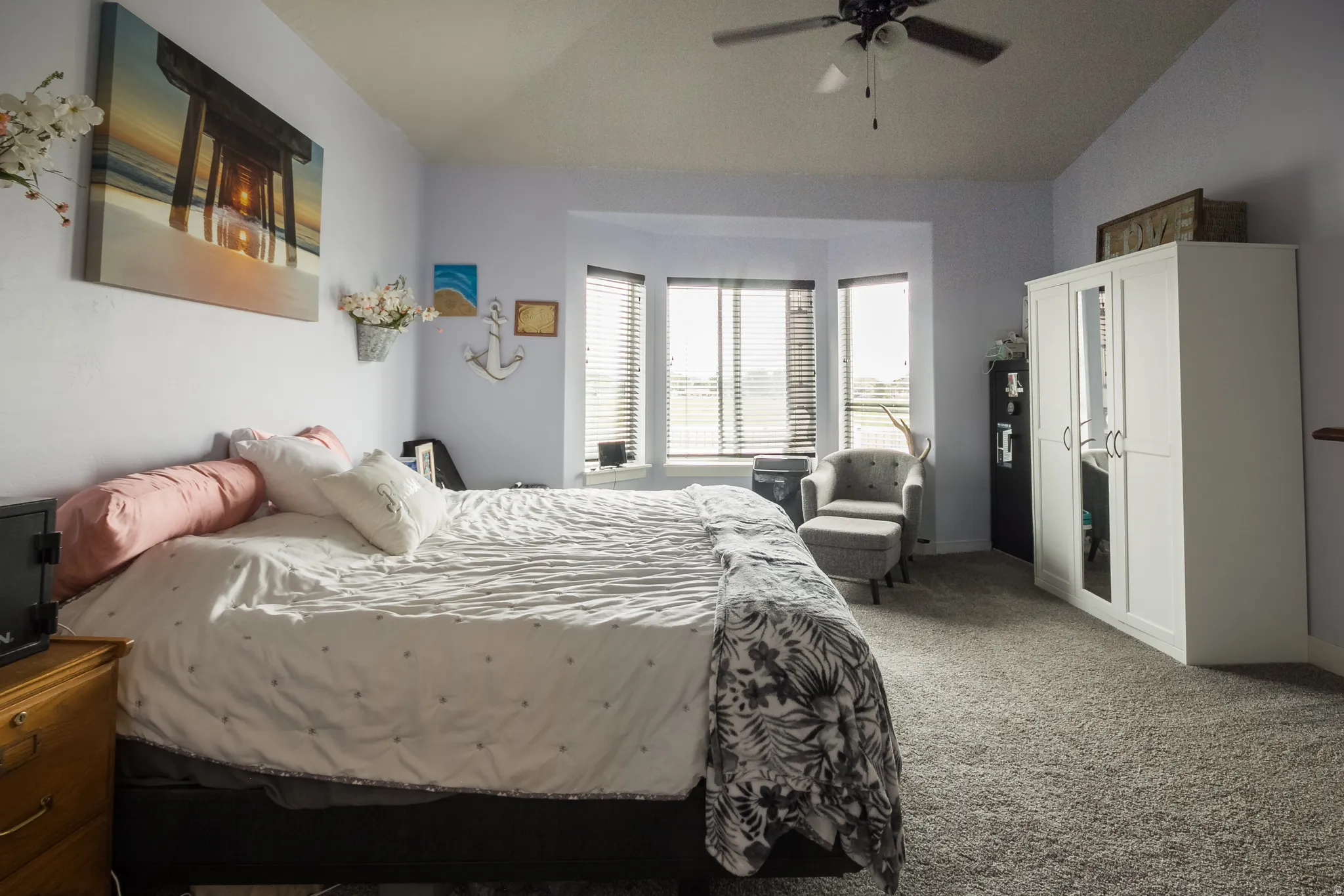 Plush carpet flooring, ceiling fan light fixture, and a bay window with blinds