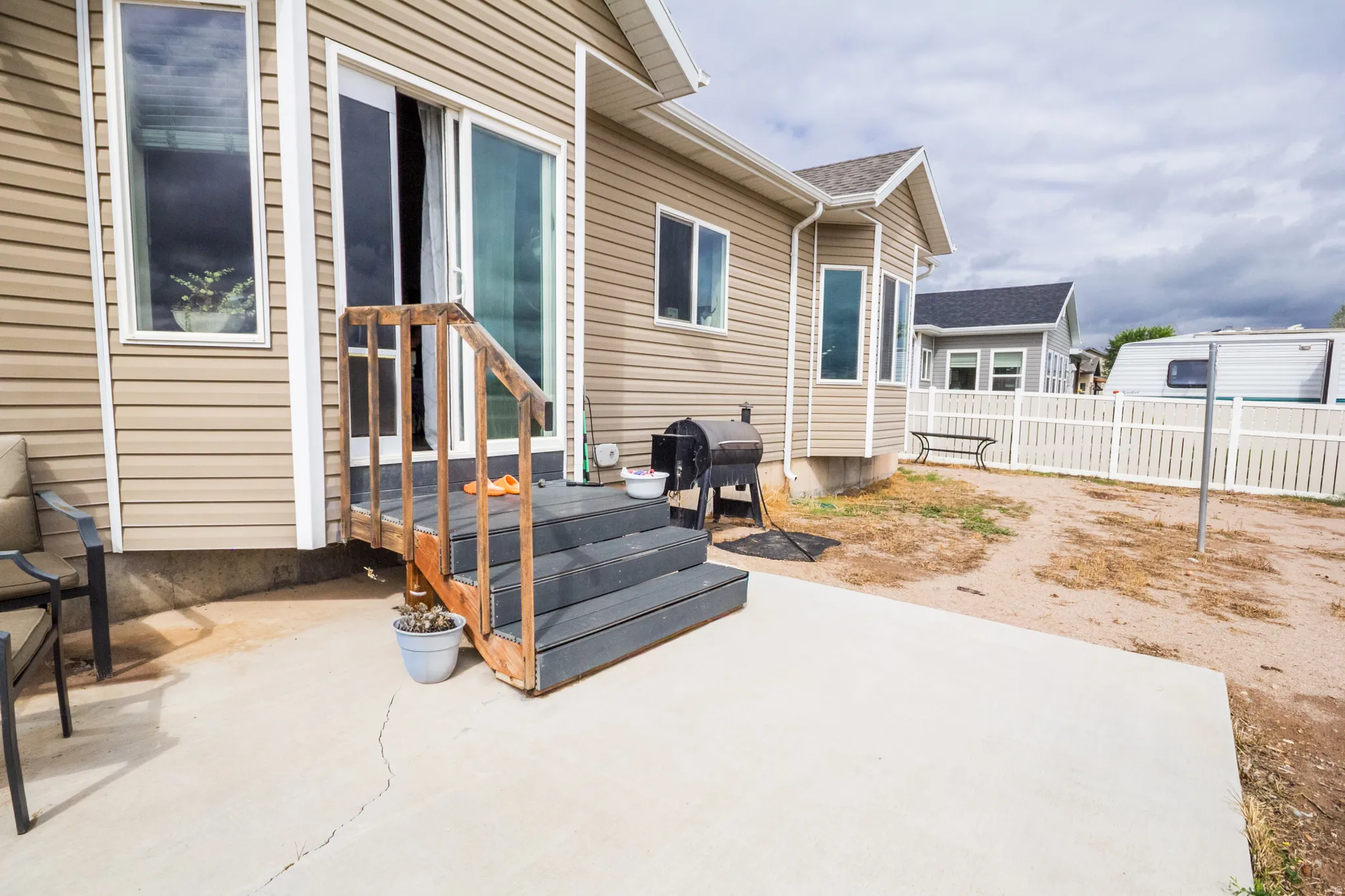 Exterior featuring tan siding, a concrete patio, and a bay window