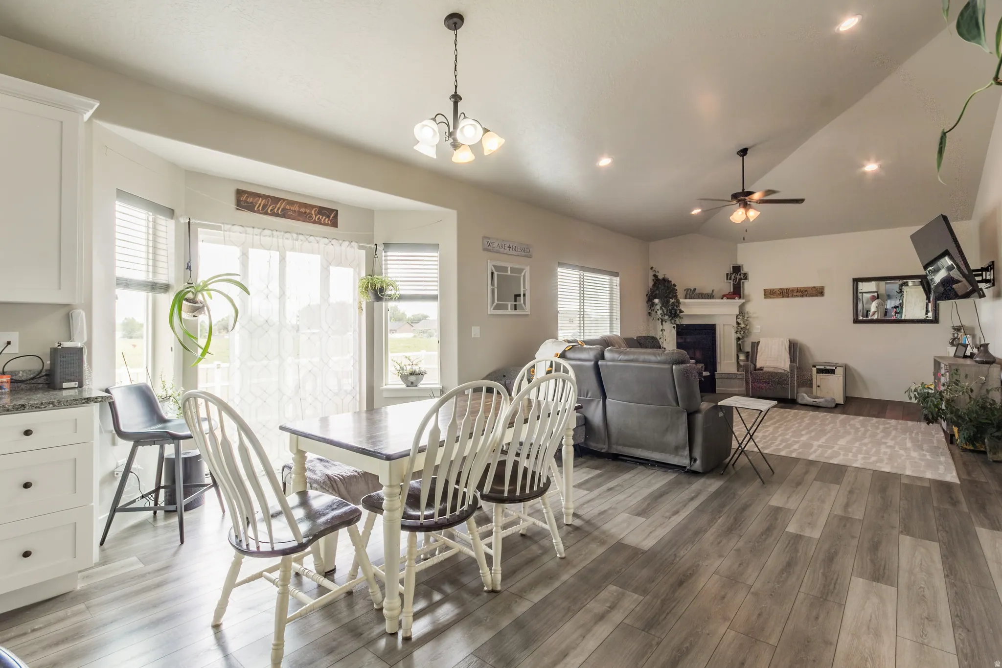 Open-concept design featuring wood-finish flooring, a bay window, white cabinetry with dark pulls, a ceiling fan, and recessed lighting