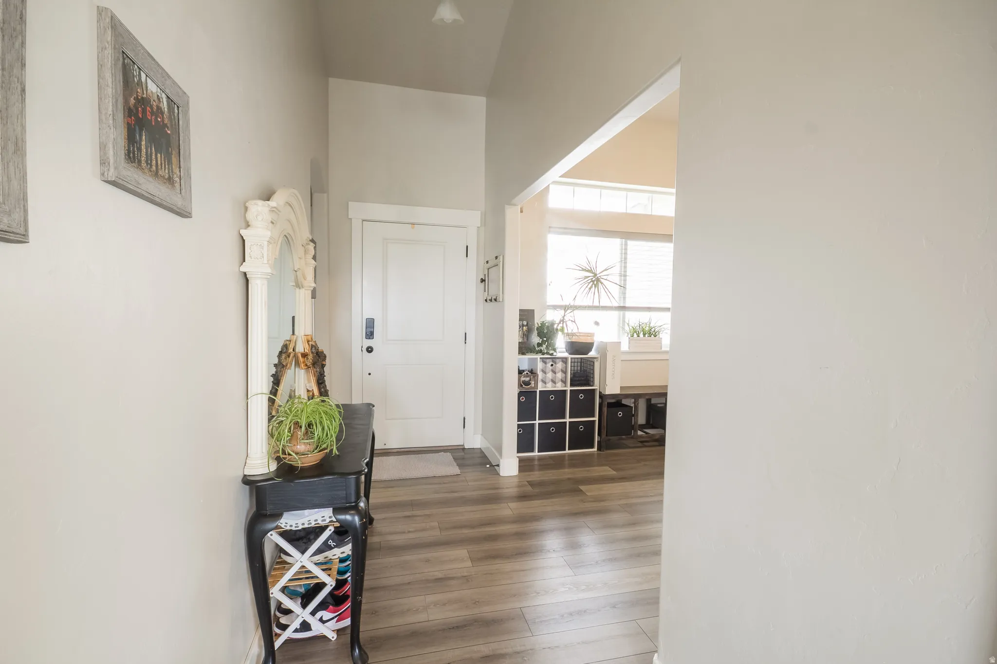 Wood-finish flooring throughout, complemented by a white paneled door and vaulted ceiling