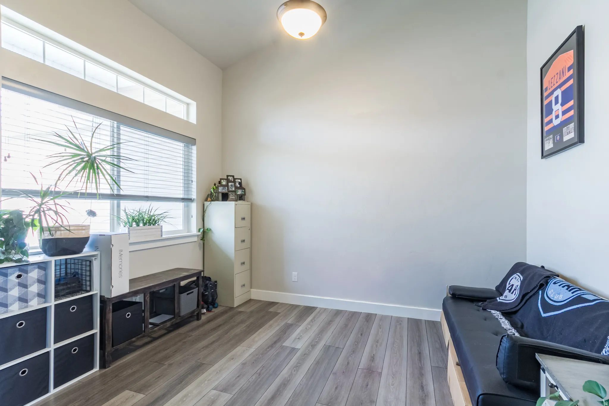 Formal Living Room or Office Wood-finish flooring, high ceilings, large window with blinds, and transom window