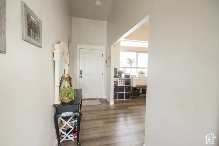Wood-finish flooring throughout, complemented by a white paneled door and vaulted ceiling