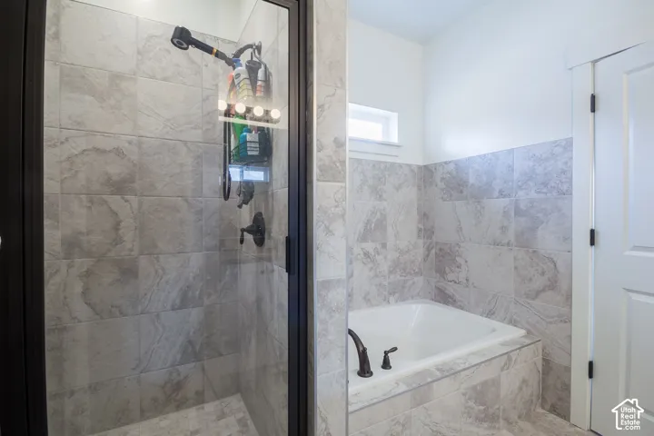 Tiled shower enclosure with a dark-framed glass door, featuring a built-in bathtub with dark bronze fixtures