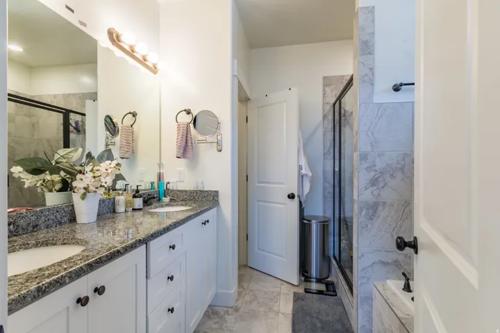 Dual vanity with stone countertop, undermount sinks, and white cabinetry