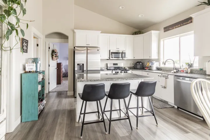 Kitchen featuring white cabinetry, granite-finish countertops, stainless steel appliances, and wood-finish flooring