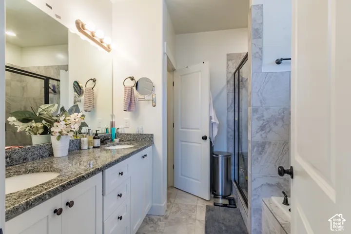 Dual vanity with stone countertop, undermount sinks, and white cabinetry