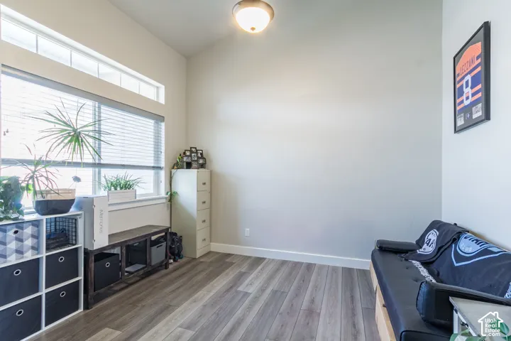 Formal Living Room or Office Wood-finish flooring, high ceilings, large window with blinds, and transom window