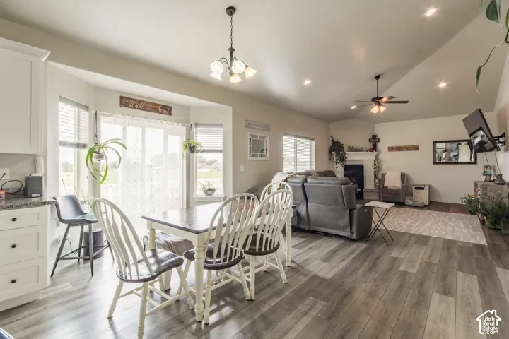 Open-concept design featuring wood-finish flooring, a bay window, white cabinetry with dark pulls, a ceiling fan, and recessed lighting
