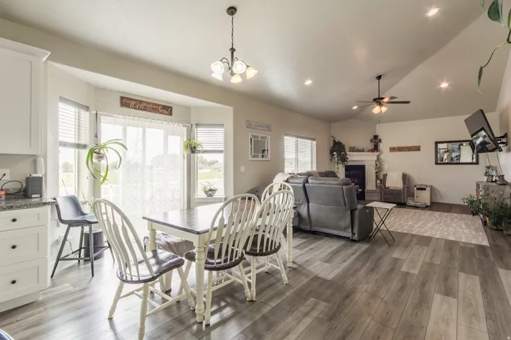 Open-concept design featuring wood-finish flooring, a bay window, white cabinetry with dark pulls, a ceiling fan, and recessed lighting