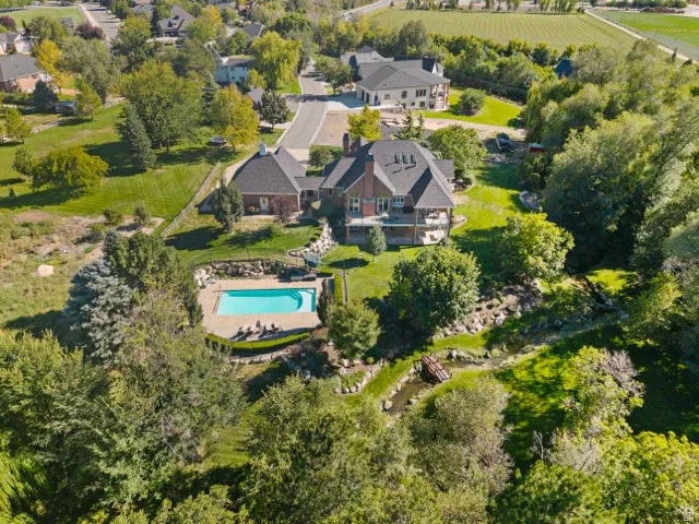 Brick exterior residence featuring a swimming pool, extensive landscaping, and a small bridge over a water feature