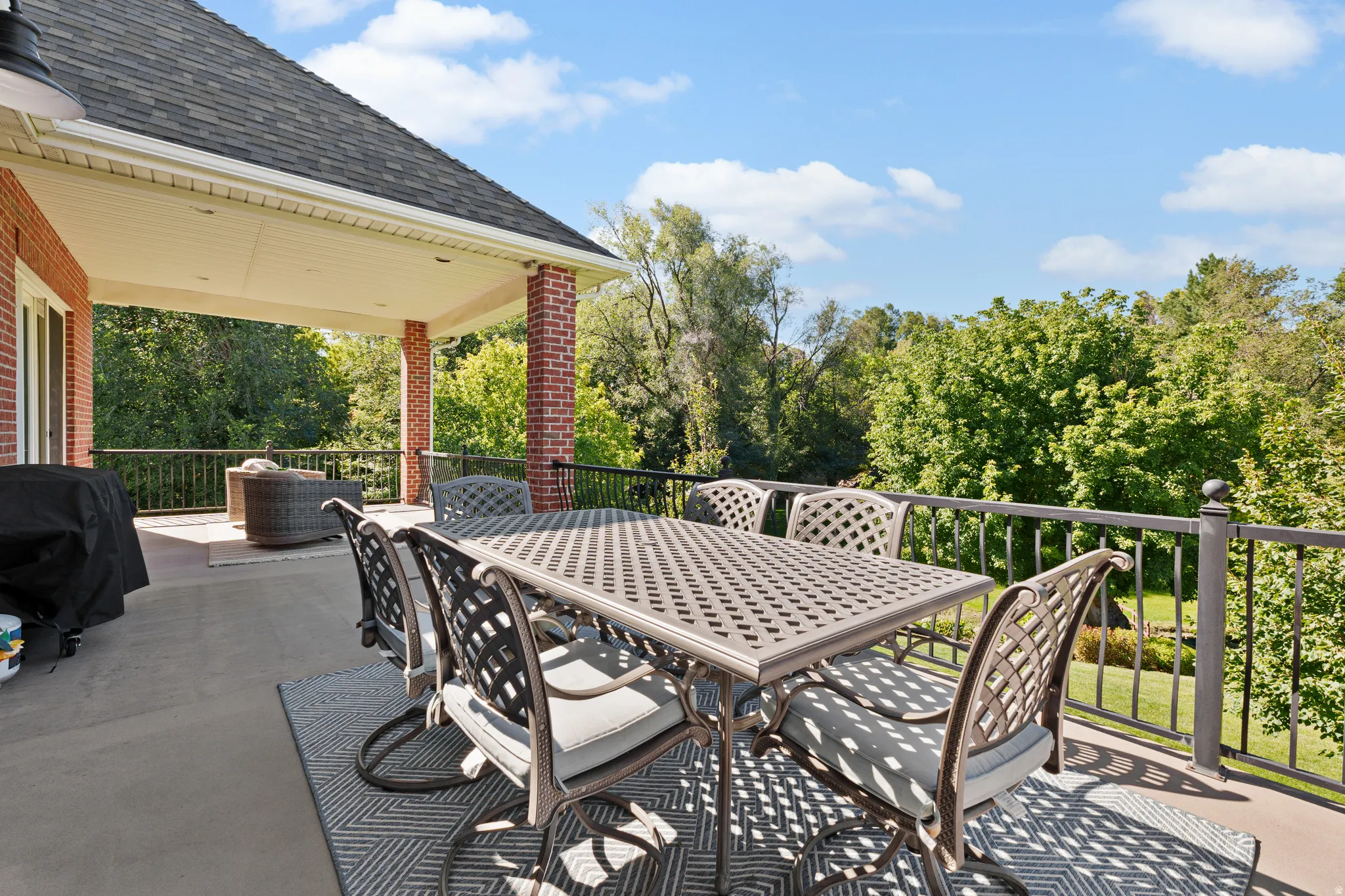 Expansive outdoor deck featuring a covered patio area, brick columns, and a black metal railing