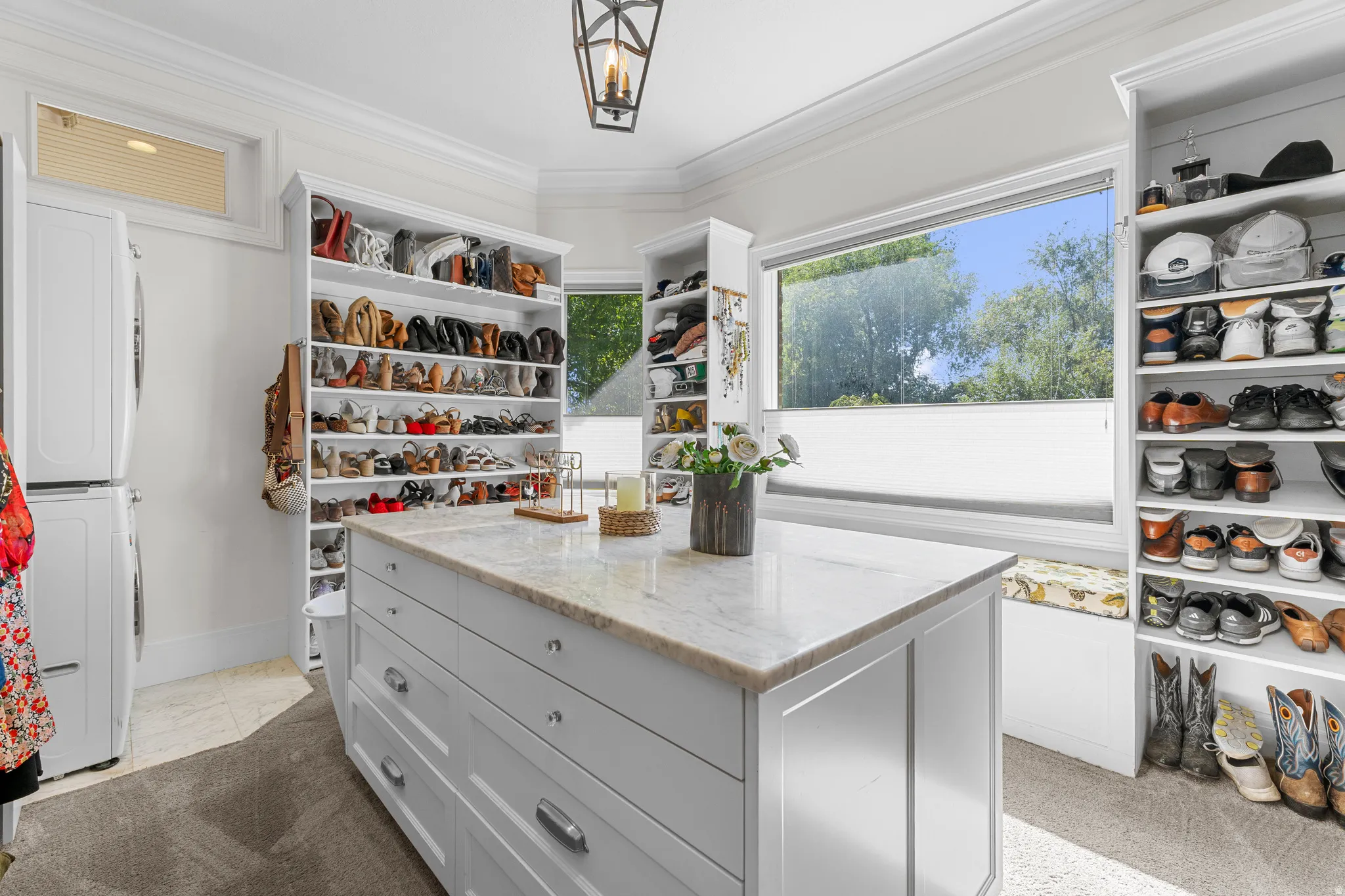 Custom closet system with built-in shelving, central island with storage, and a large window