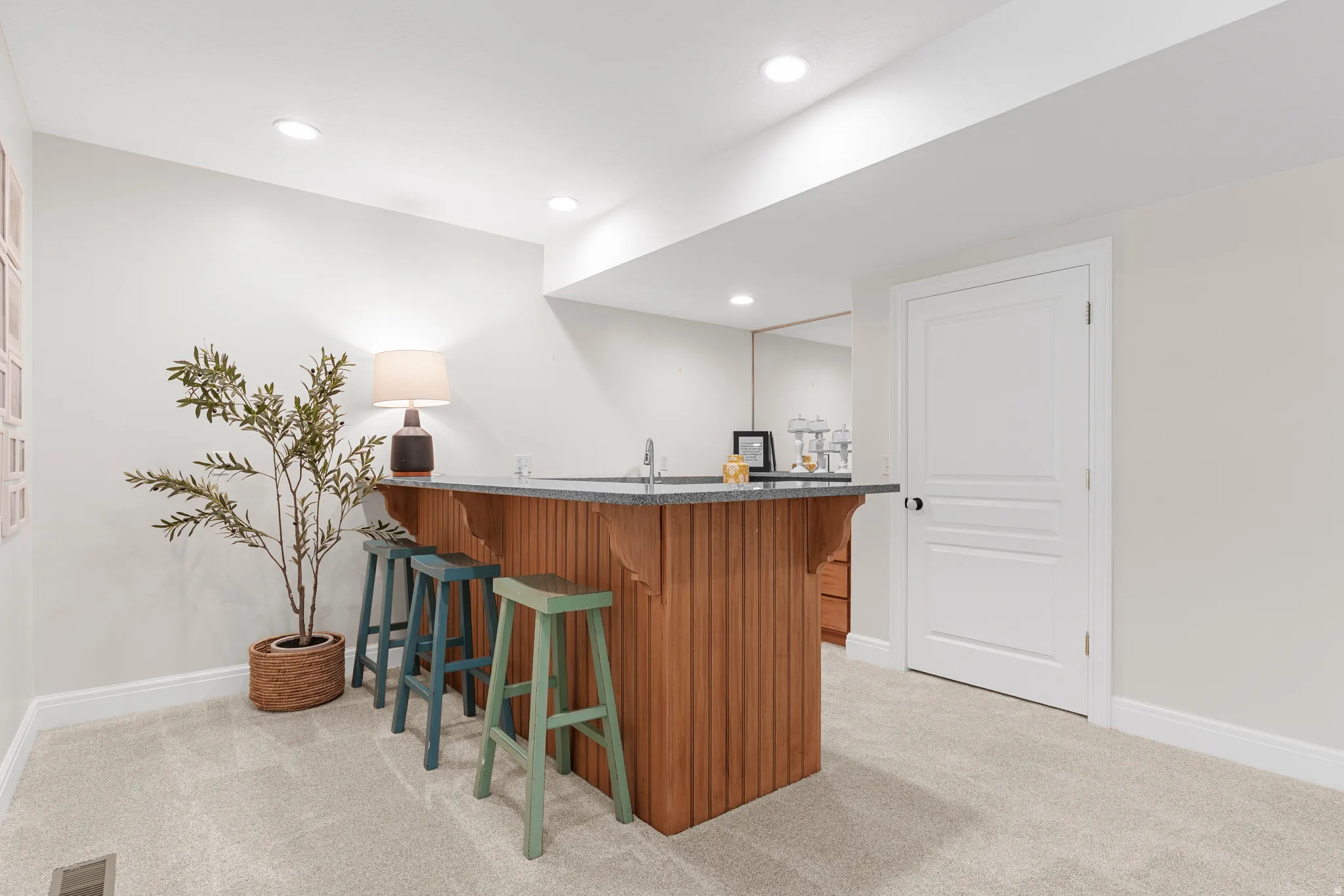 Built-in wet bar with a light wood-finish base, stone countertop, and integrated sink