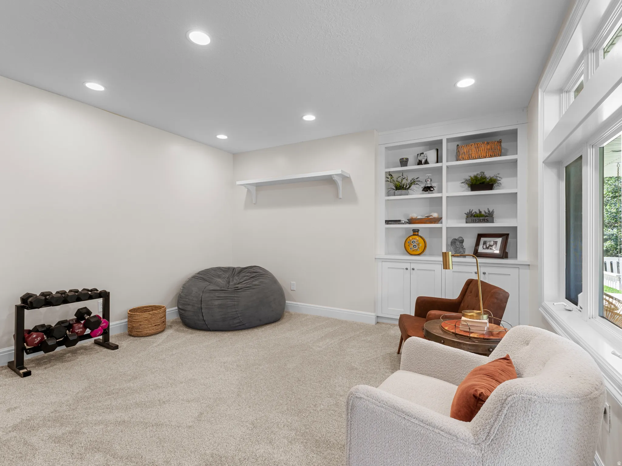 Recessed ceiling lighting, built-in shelving, white wall paint, carpeted flooring, and large windows