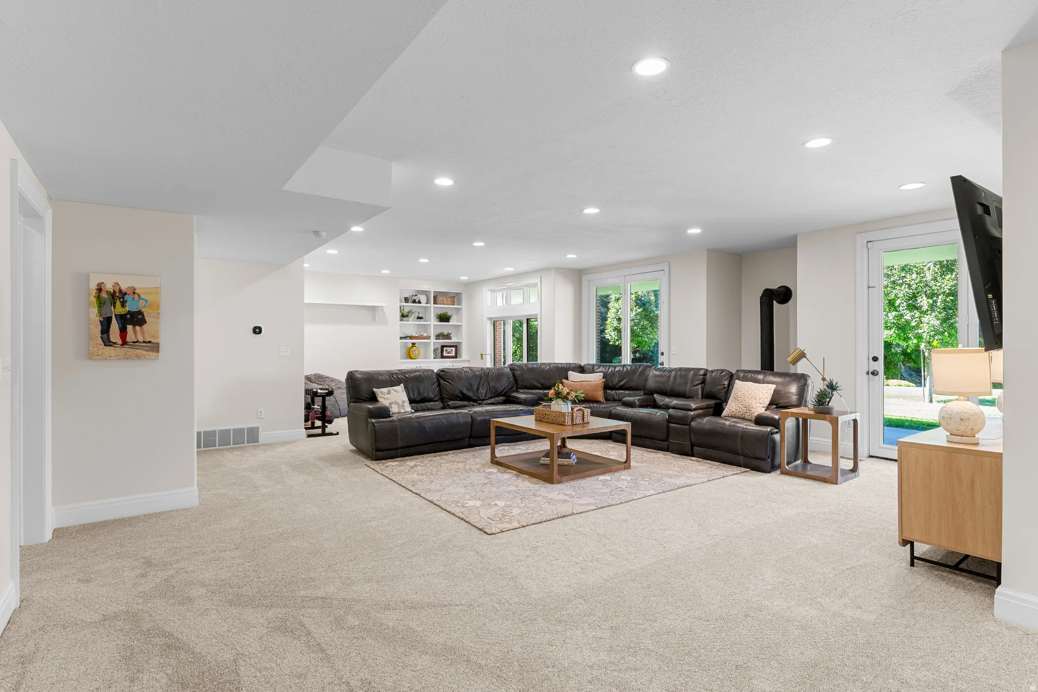 Recessed lighting, light-colored carpeting, built-in shelving, glass-paned doors, and a black wood-burning stove