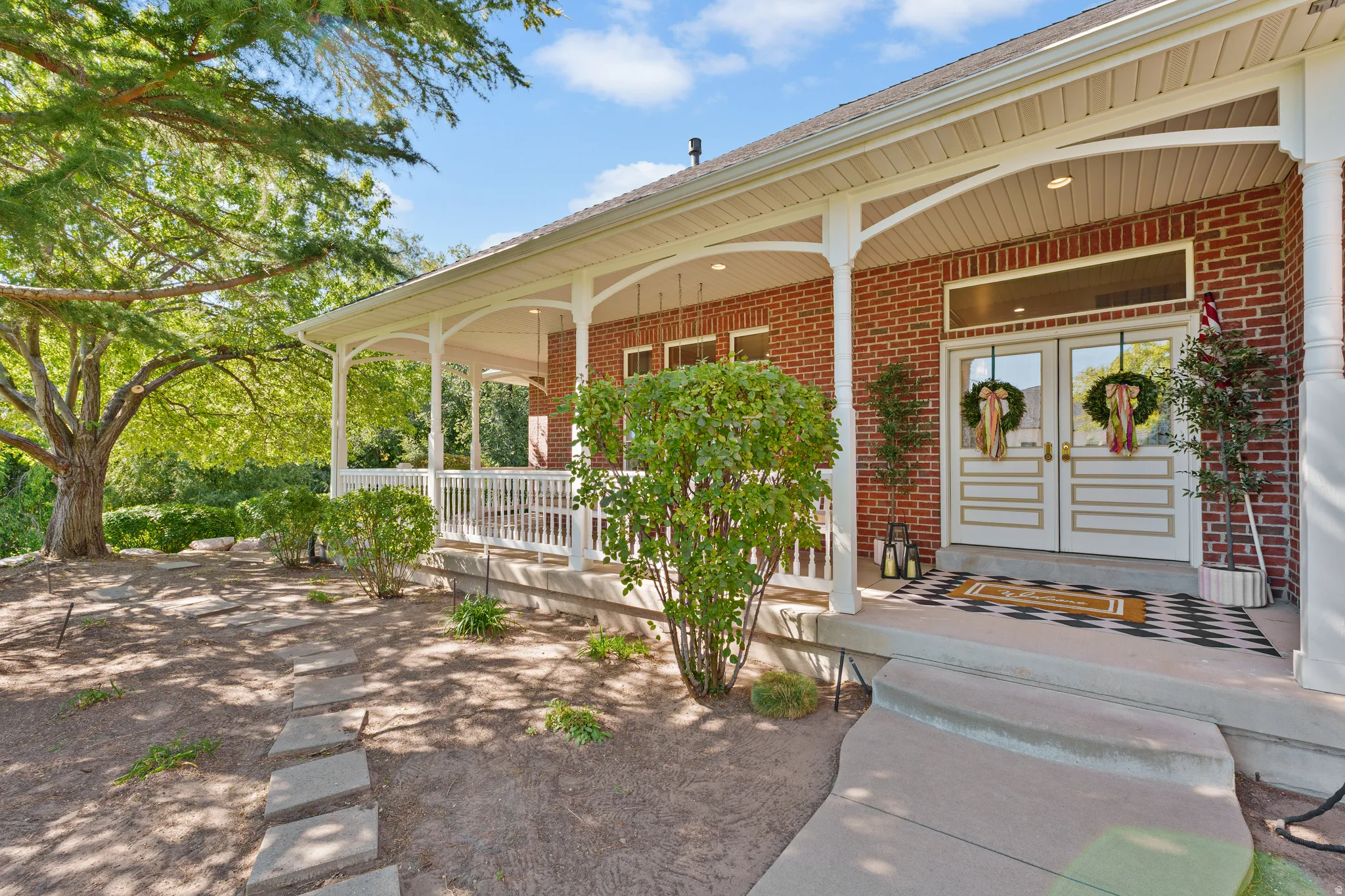 Brick facade with a covered porch featuring white columns and railing