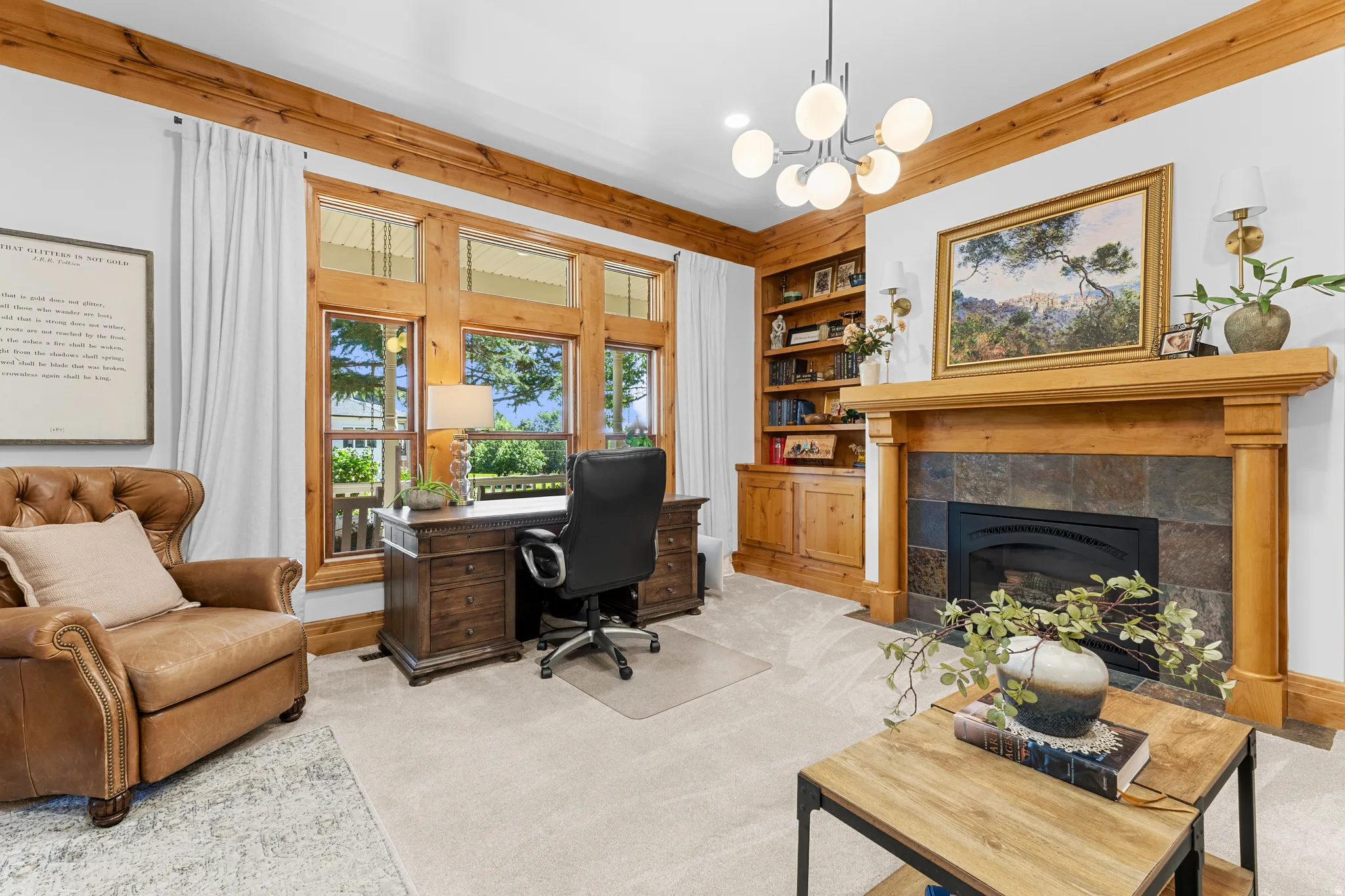 Room featuring a stone-faced fireplace with a wood mantel, built-in wood cabinetry, a large window with wood trim, and a contemporary chandelier