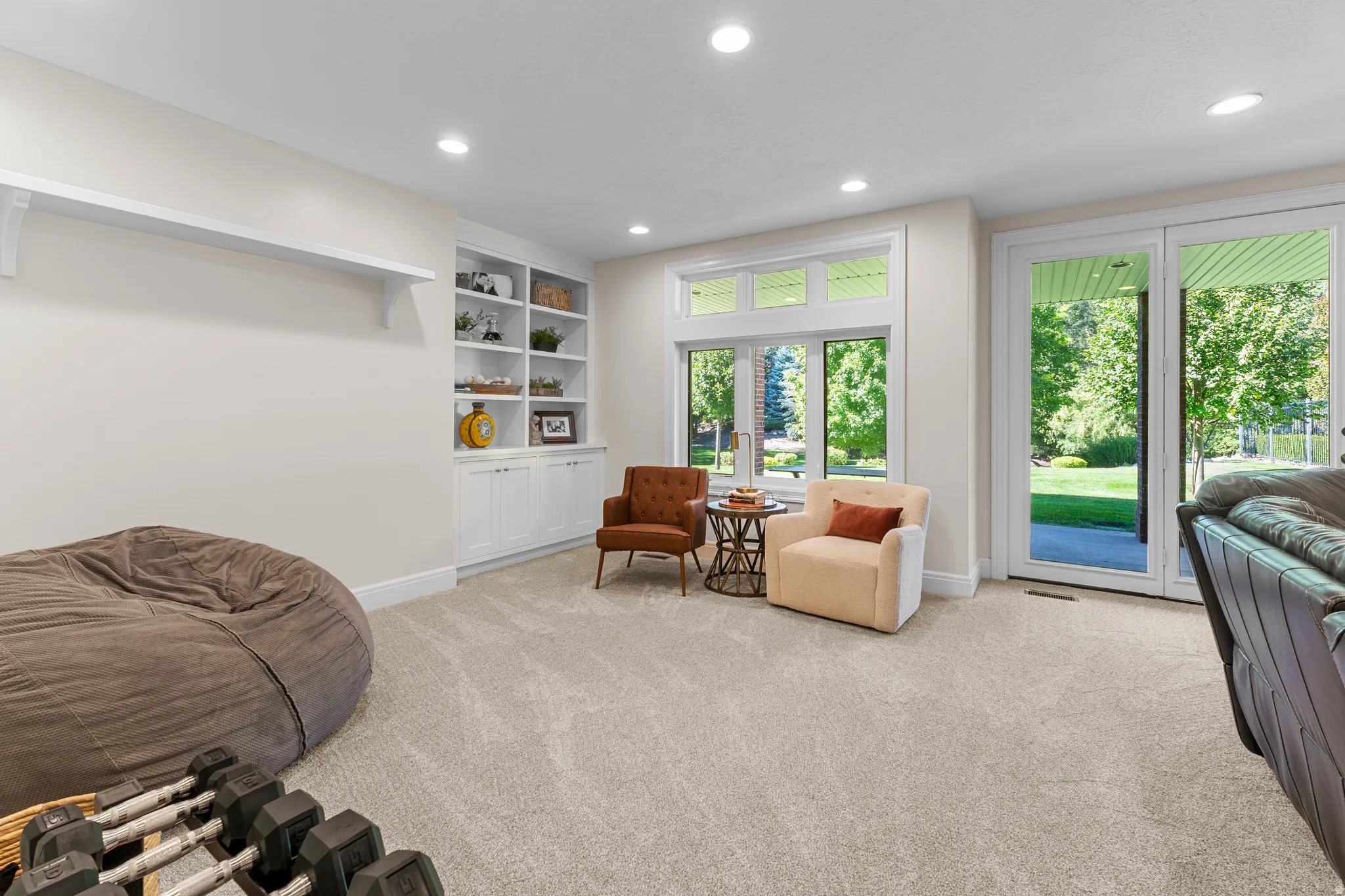 Built-in shelving, recessed ceiling lighting, light-toned carpet, large windows, and glass paneled doors