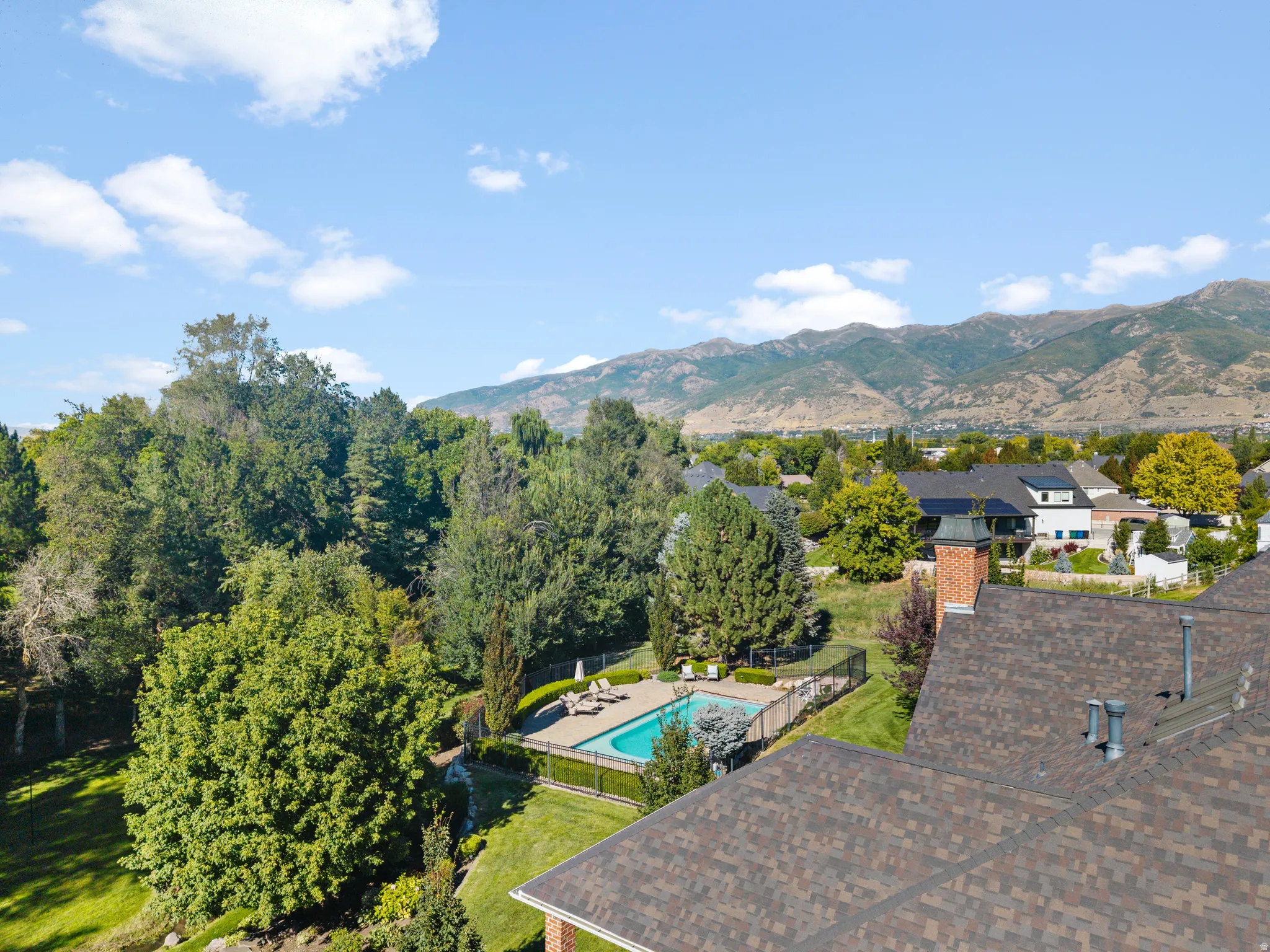 Expansive outdoor living area featuring a swimming pool with integrated hardscaping, fenced surround, and mature landscaping