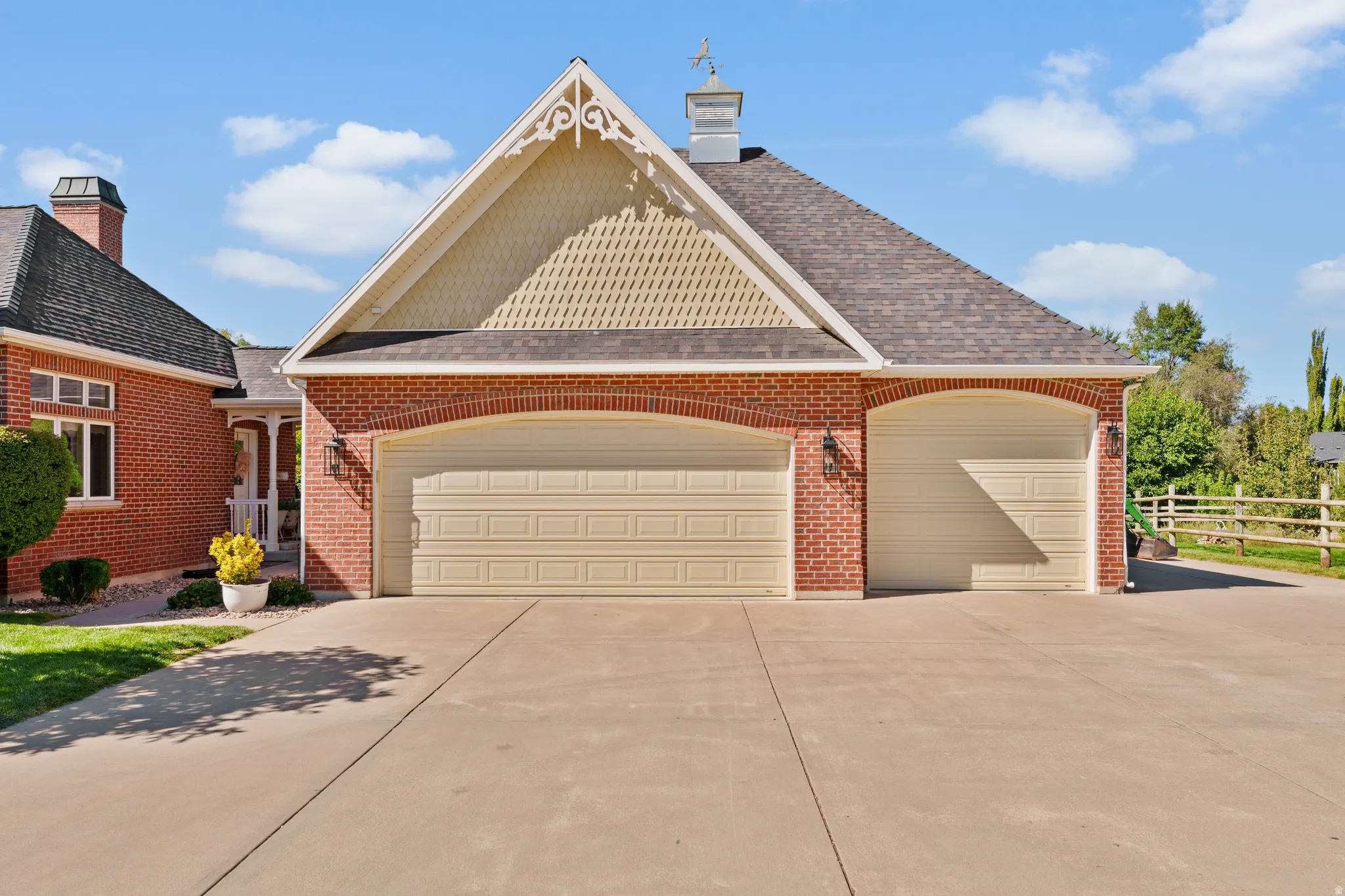 three-car garage with arched brick detailing, a cupola with weather vane, and decorative gable trim