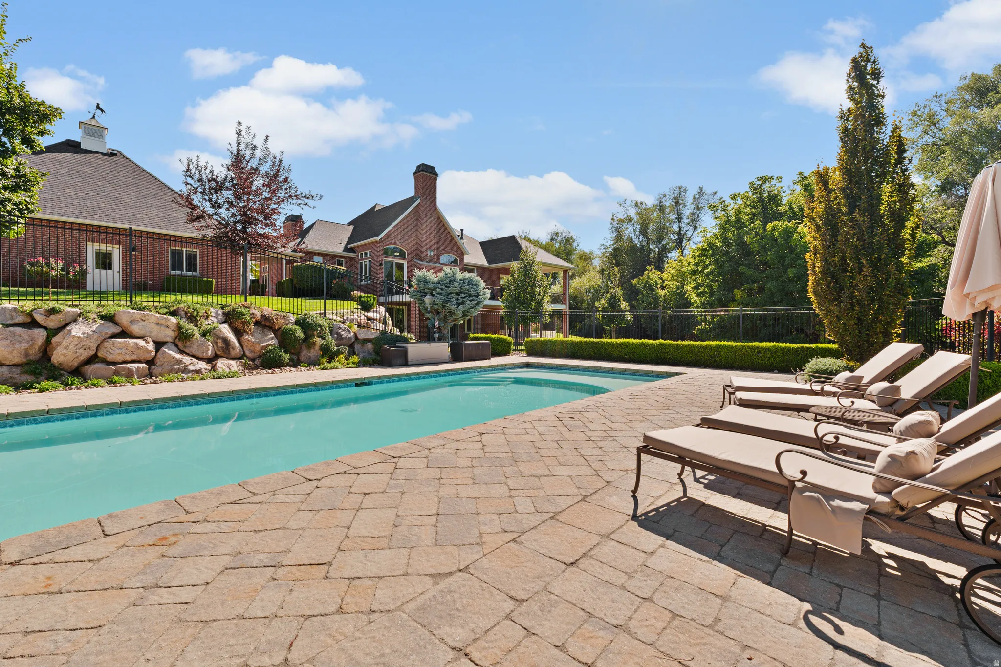 Swimming pool with a paver patio and rock retaining wall