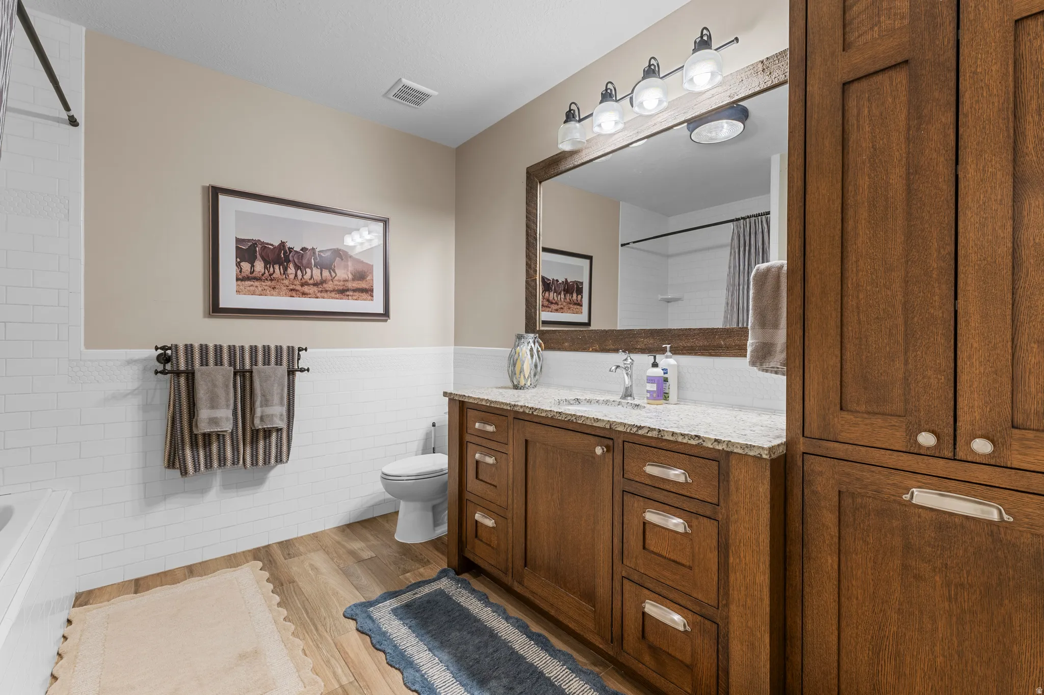 Wood-finish flooring with a white subway tile wainscoting