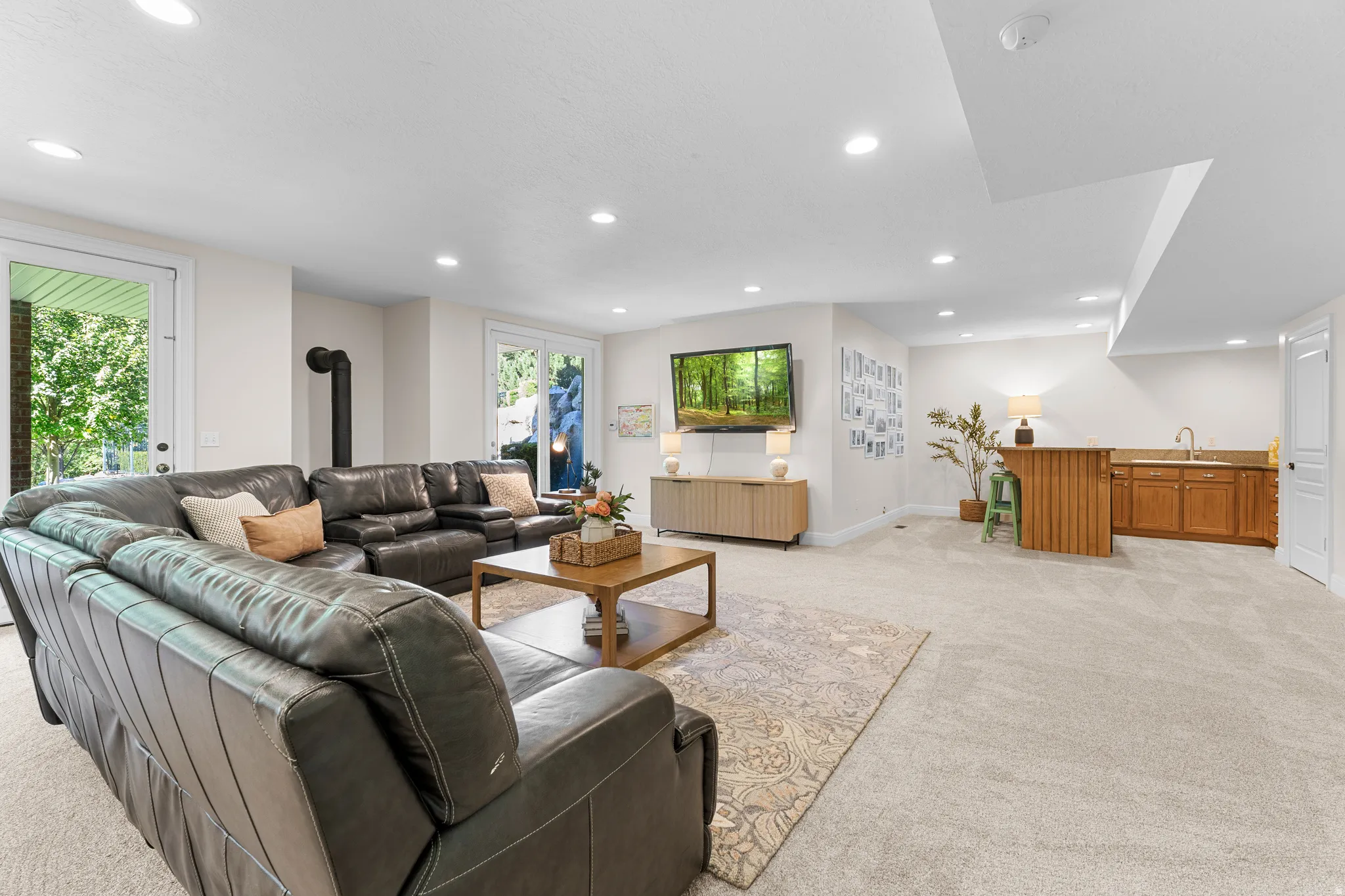 Recessed lighting, light-toned carpeting, built-in wet bar with wood cabinetry, white walls, and bright white trim