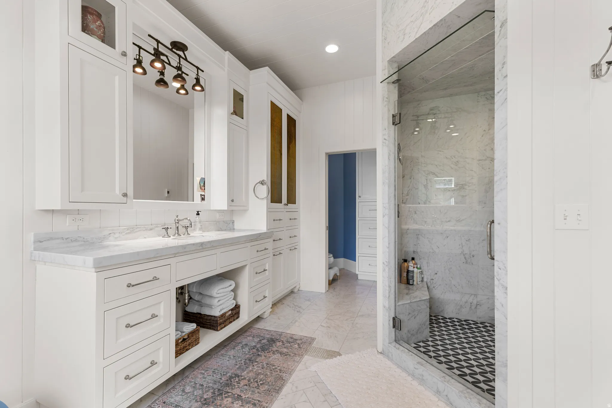 Double vanity with undermount sinks, stone countertops, and extensive white cabinetry