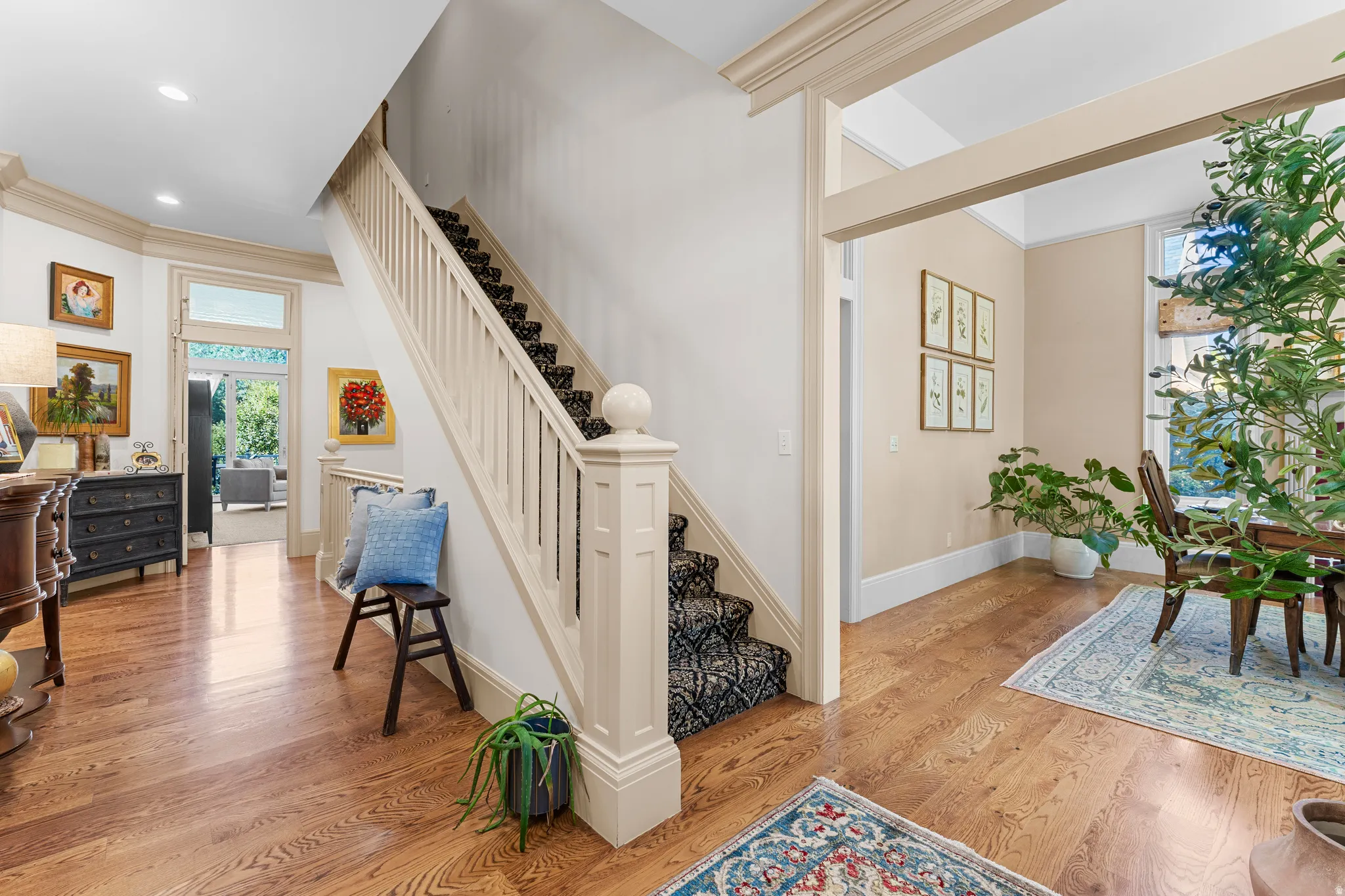 Hardwood flooring throughout, a grand staircase with decorative balusters, and a wide entryway with a transom window