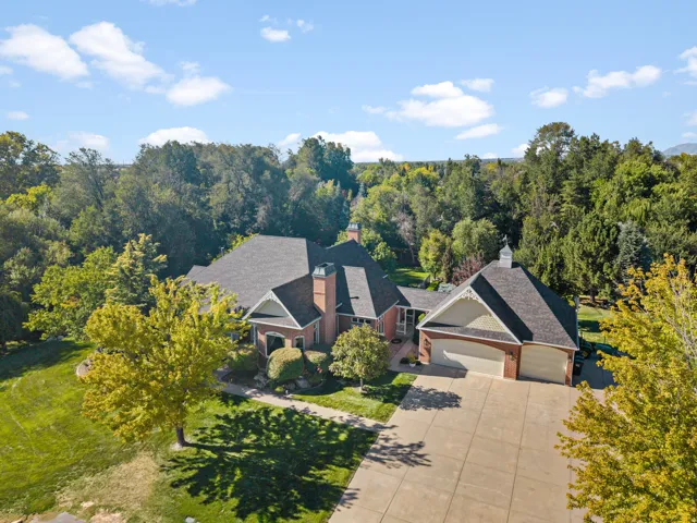 Expansive paved driveway leading to a three-car garage with brick detailing