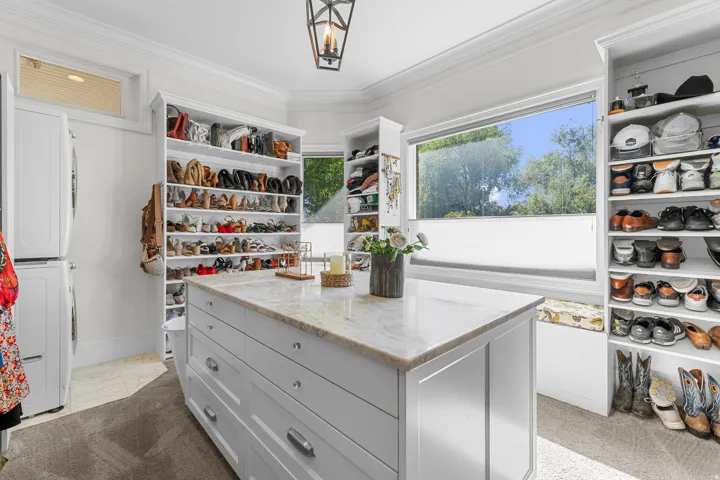 Custom closet system with built-in shelving, central island with storage, and a large window