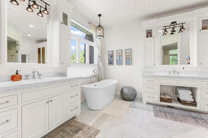 Dual vanity with white cabinetry and stone countertops, freestanding soaking tub, shiplap wall paneling.