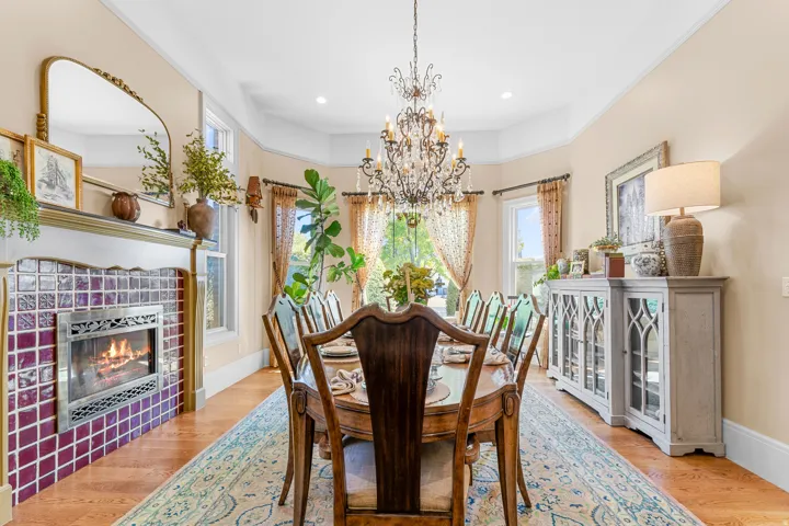 Wood-finish flooring, tiled fireplace surround, ornate chandelier, bay window, and crown molding