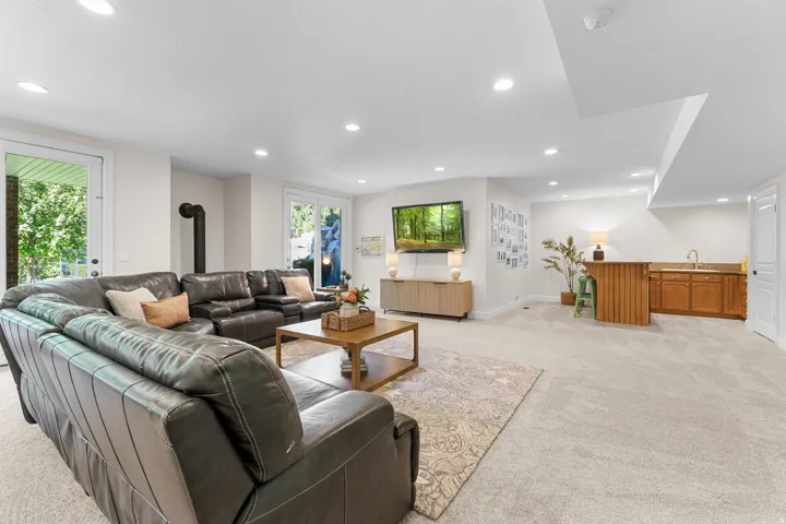 Recessed lighting, light-toned carpeting, built-in wet bar with wood cabinetry, white walls, and bright white trim