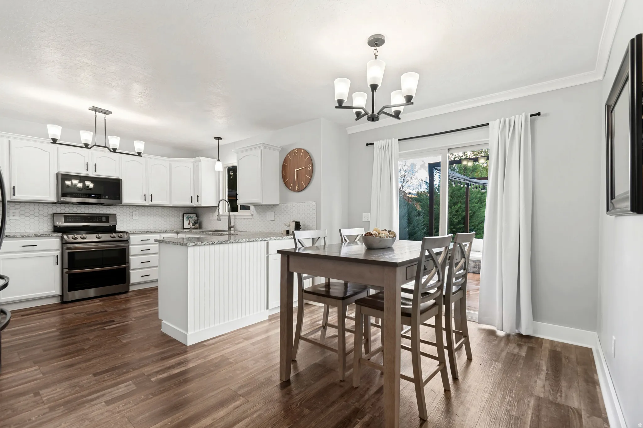 Kitchen featuring white cabinetry, stainless steel appliances, a center island with beadboard detailing, and wood-finish flooring
