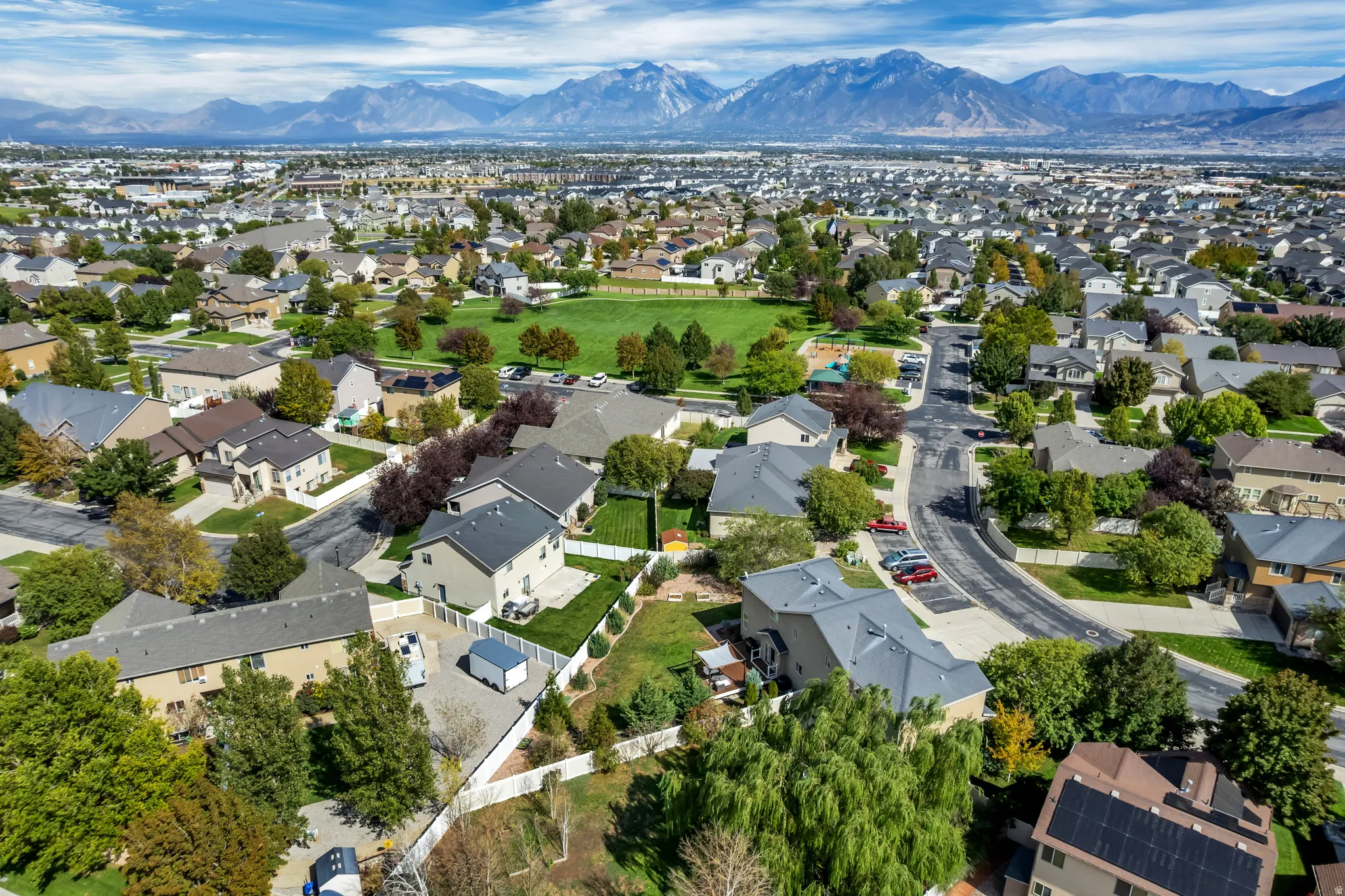 Expansive residential area featuring a central green space, paved streets, and a mountainous backdrop