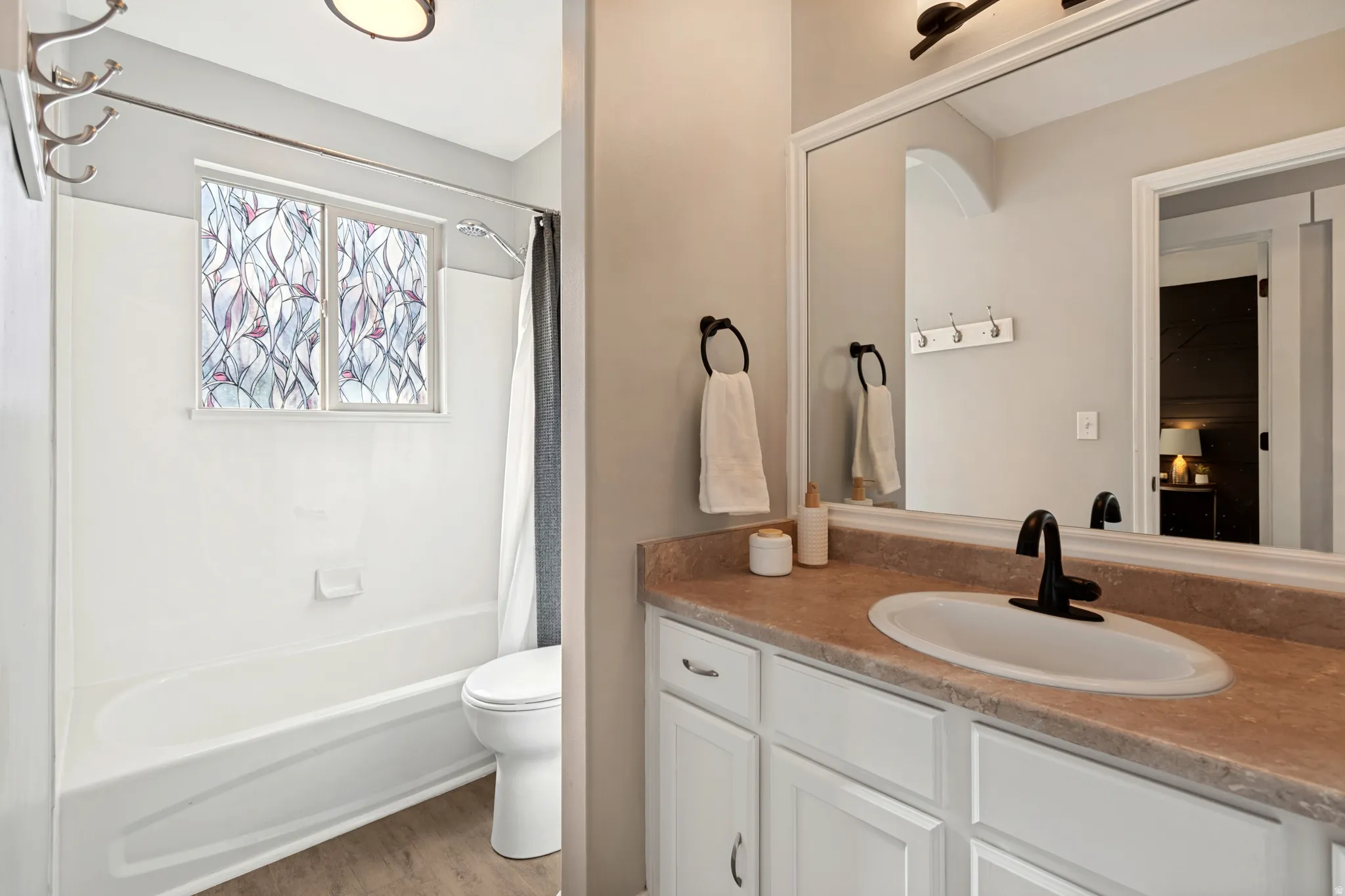 Bathroom featuring a white vanity with built-in cabinetry, a rectangular undermount sink, and a dark-finish faucet