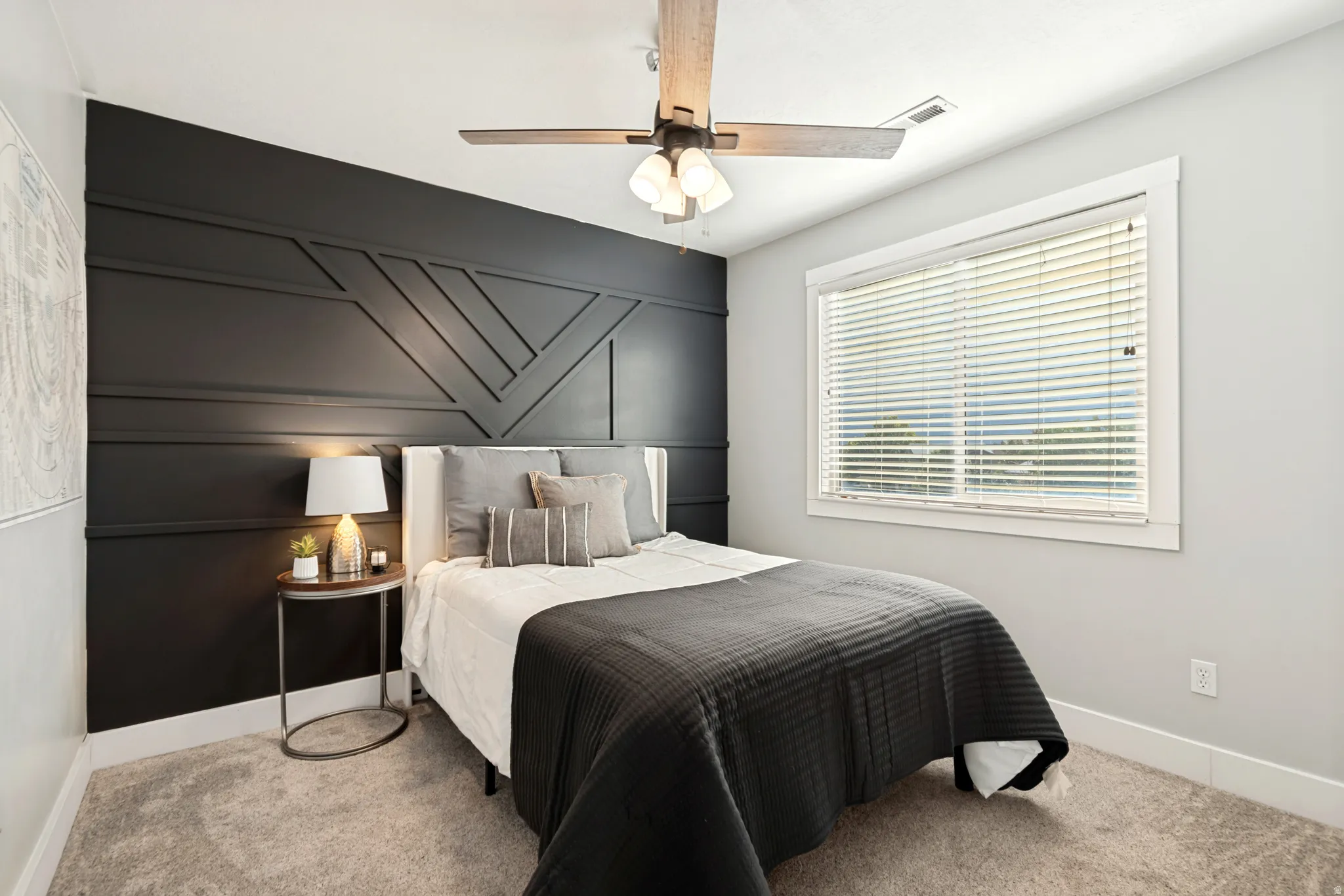 Accent wall featuring geometric paneling, ceiling fan with light fixture, window with blinds, and neutral carpeting