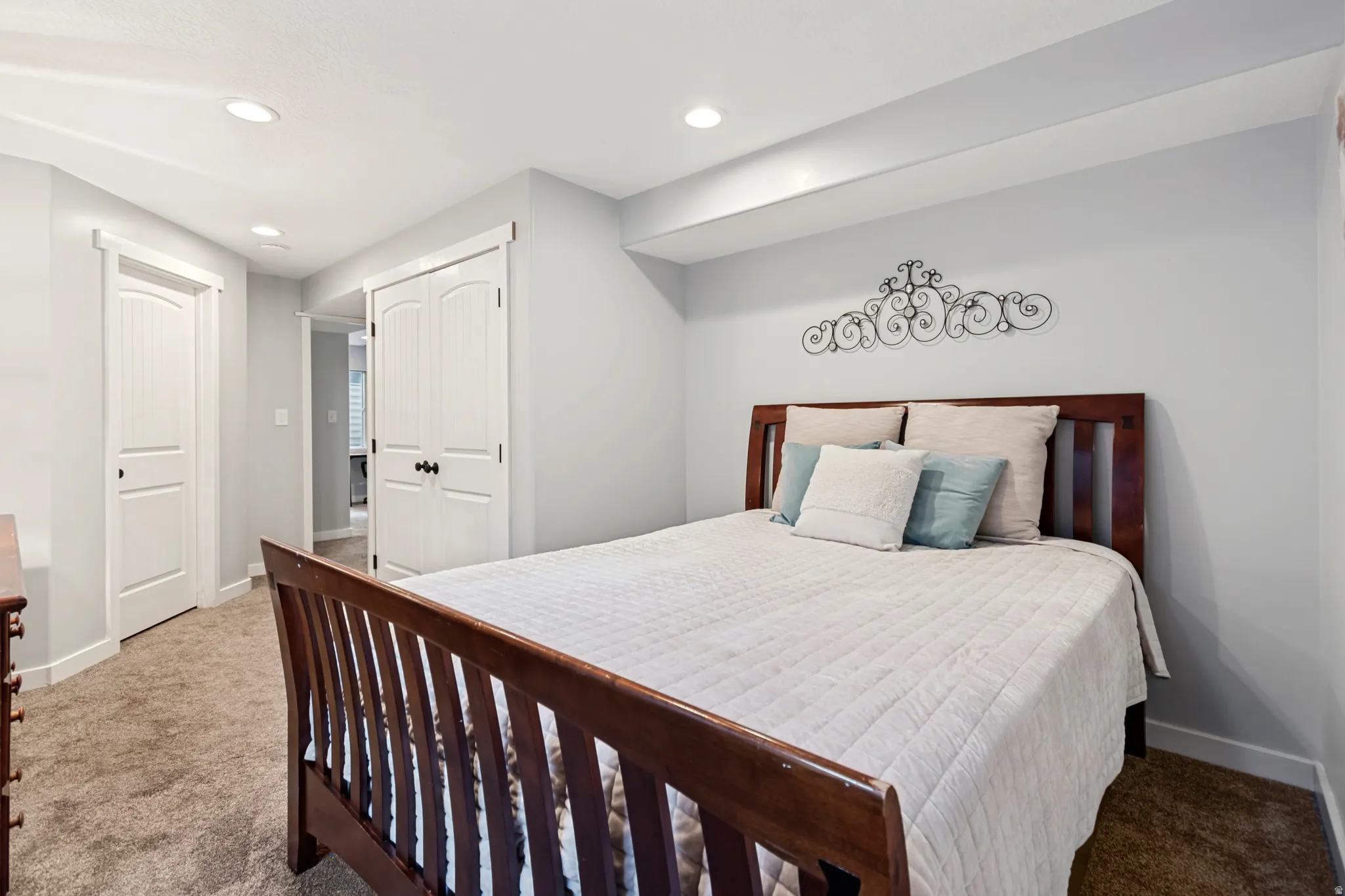 Recessed lighting, light gray wall paint, white trim, wood-finish headboard, and carpet flooring