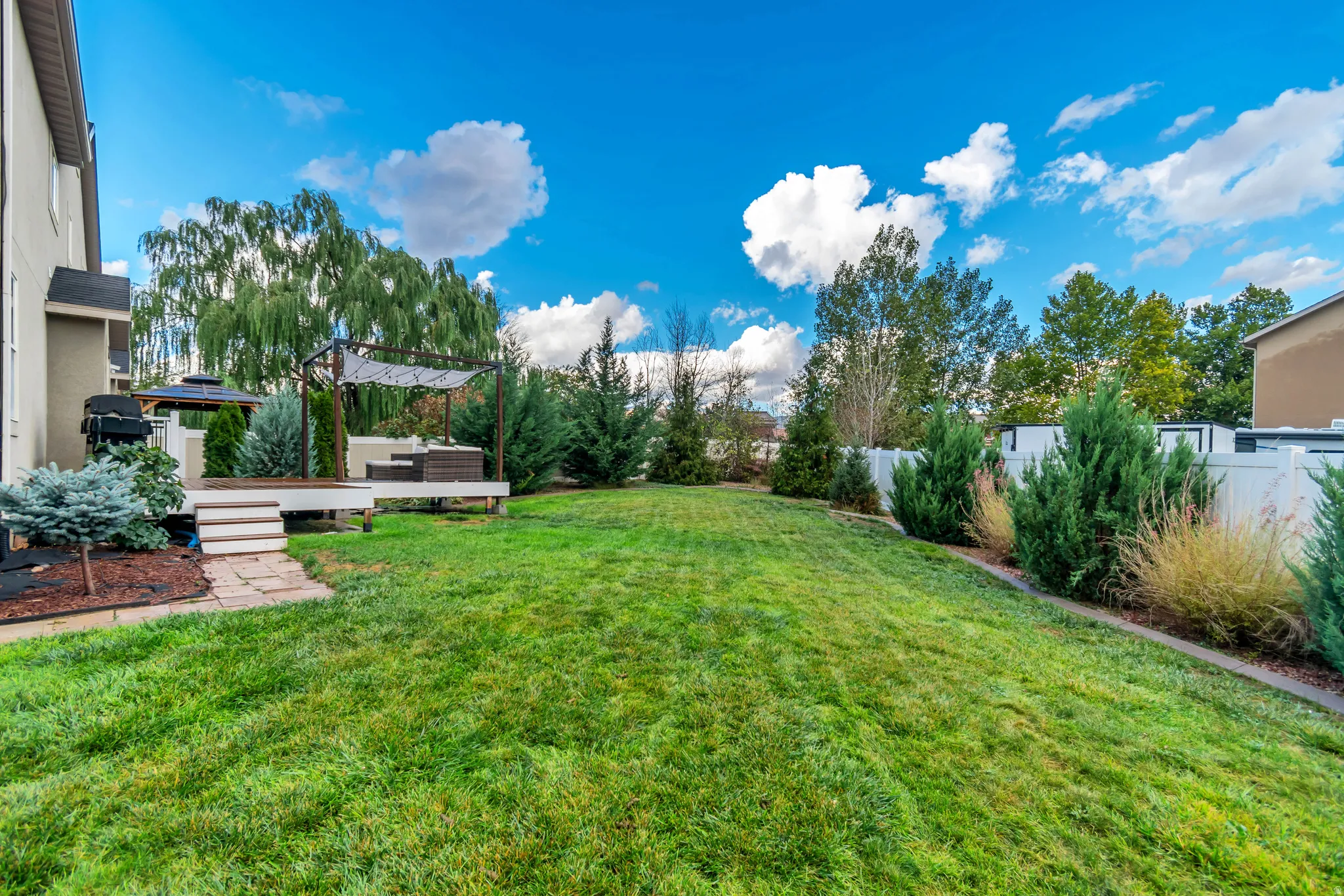 Expansive backyard featuring a lush lawn, multi-level deck, gazebo, pergola, and privacy fencing
