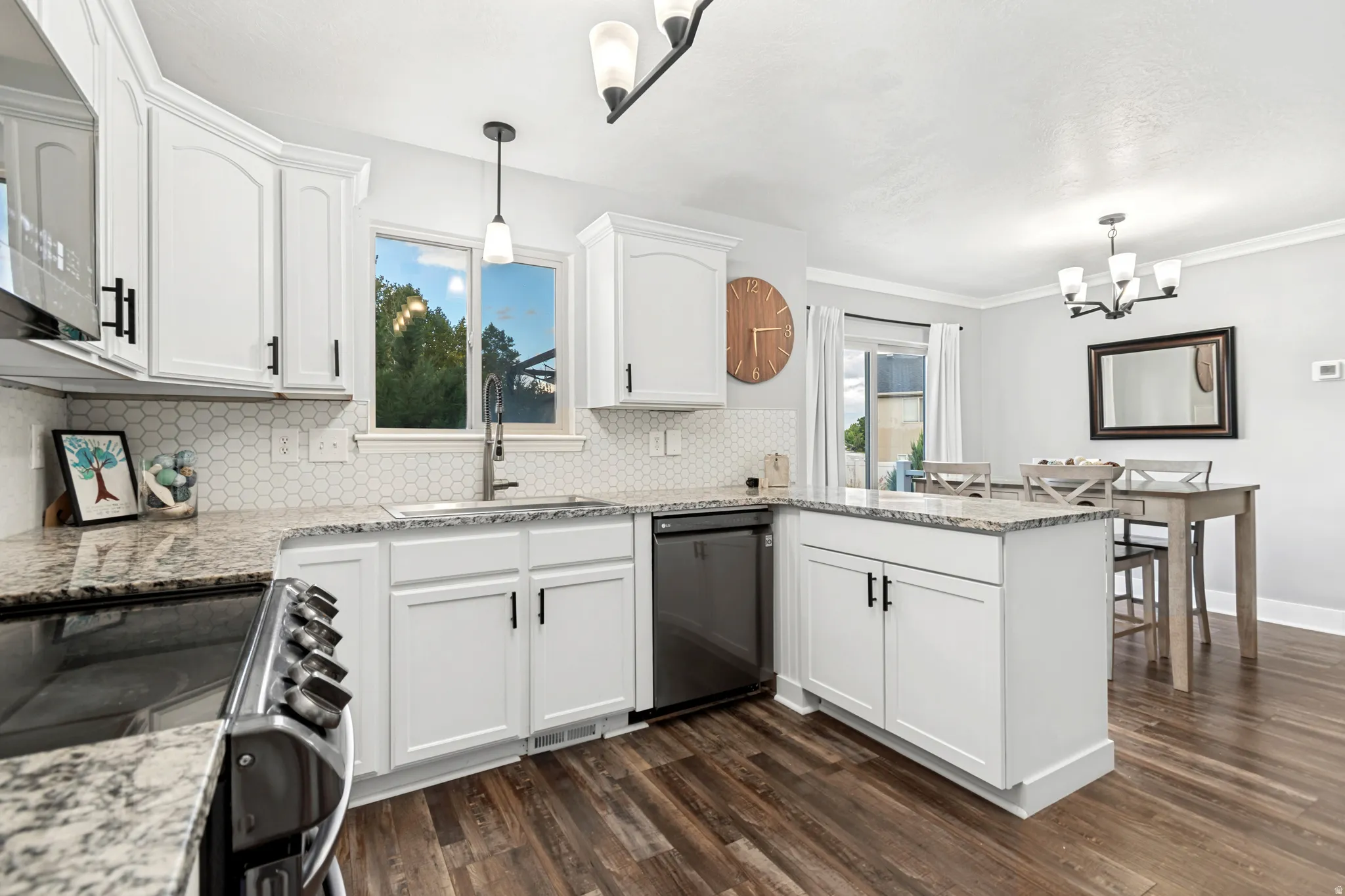 Bright kitchen featuring white cabinetry, stone countertops, a hexagonal tile backsplash, stainless steel appliances, and wood-finish flooring