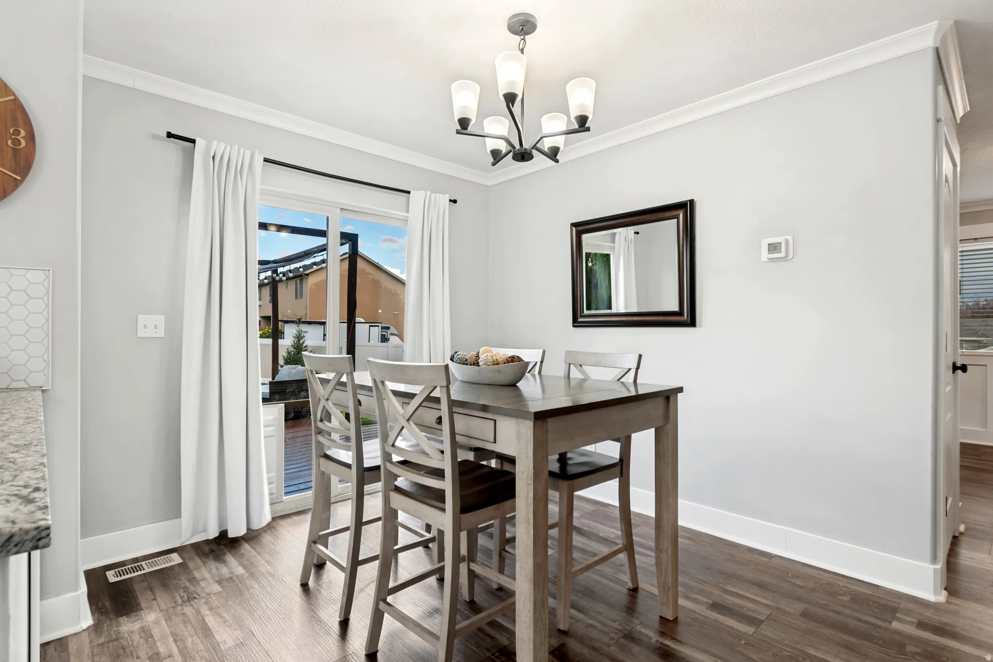 Wood-finish flooring, crown molding, and a sliding glass door