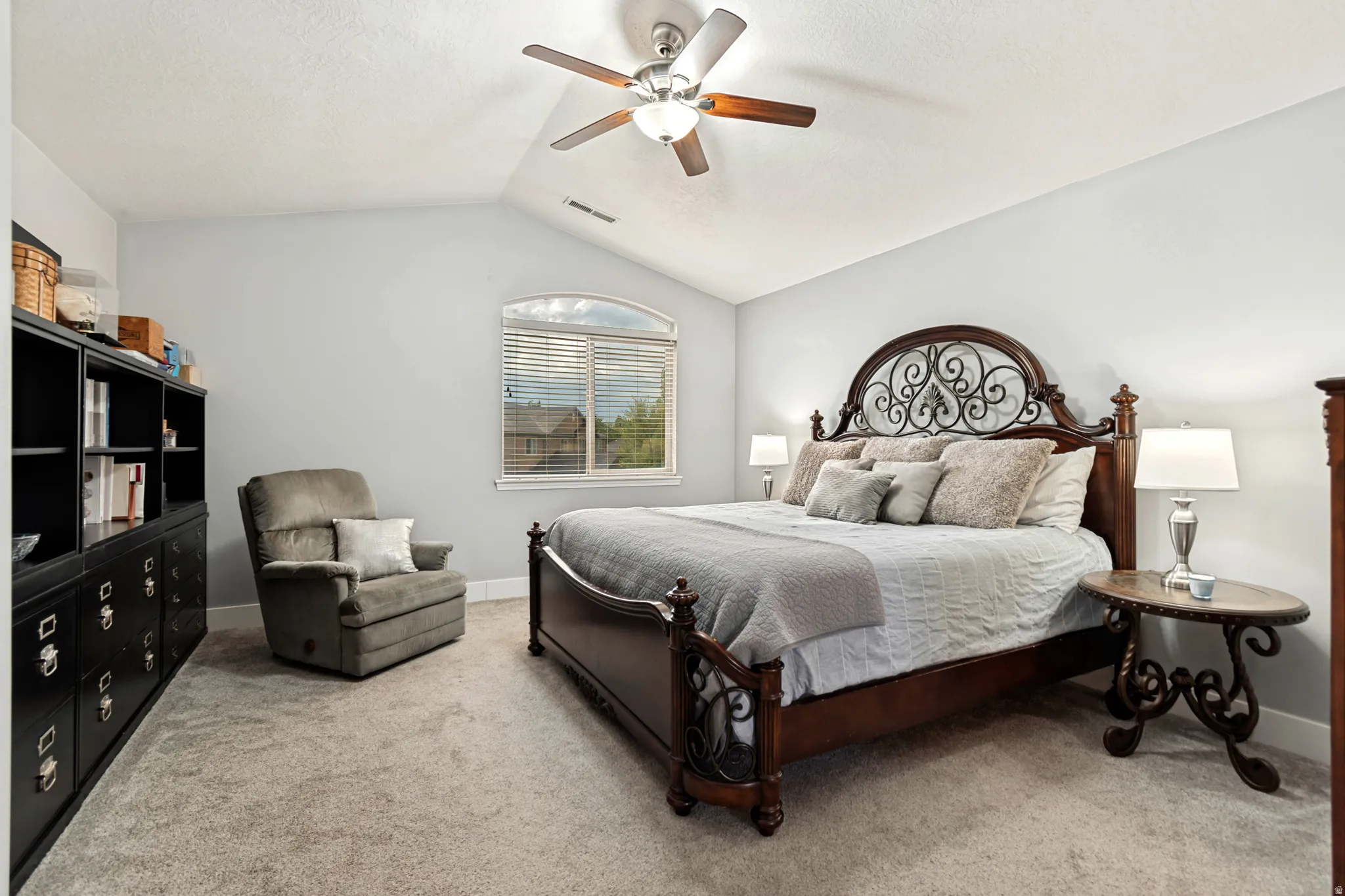 Carpeted flooring, vaulted ceiling, arched window, and a ceiling fan with integrated lighting