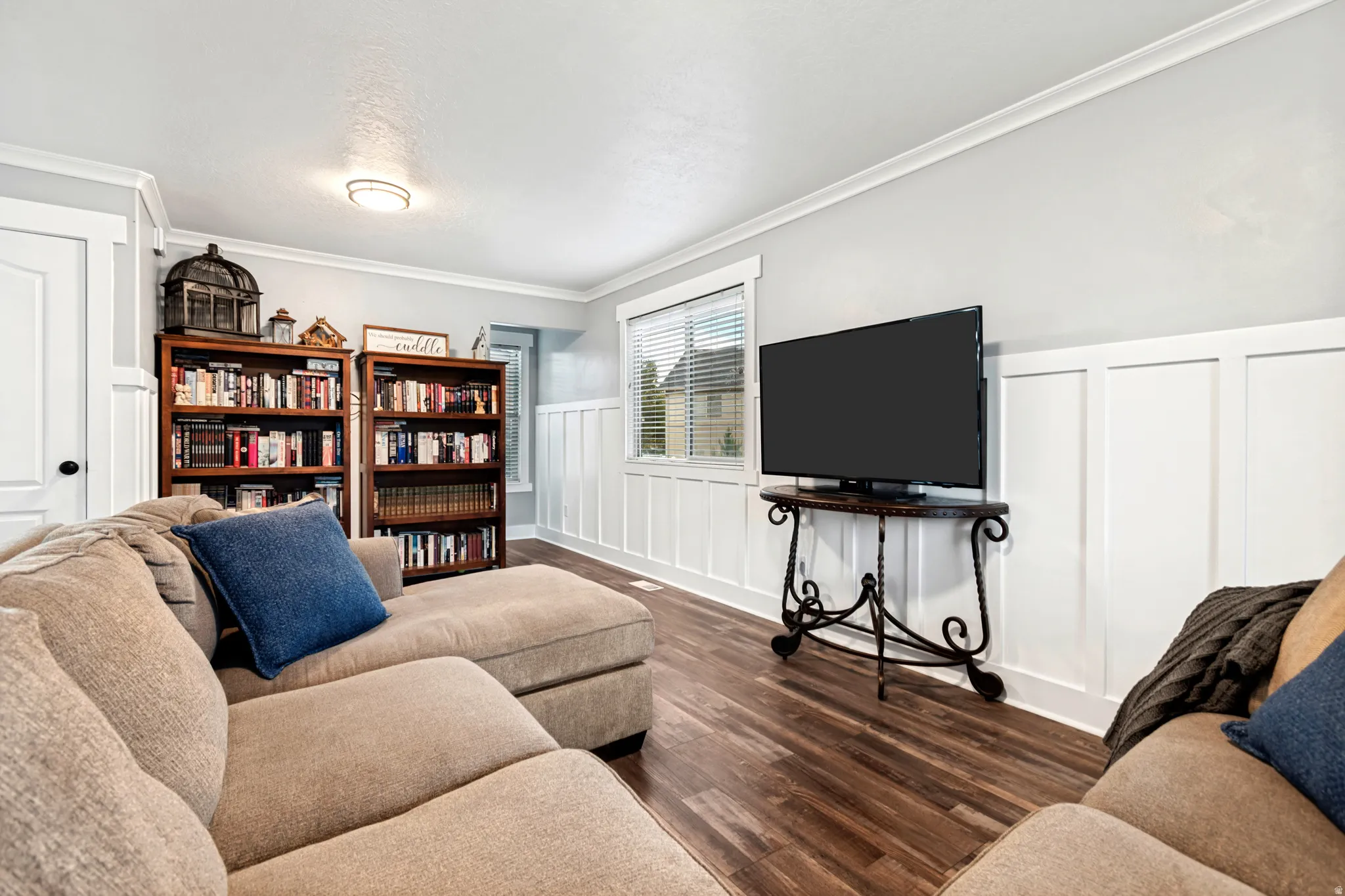 Wood-finish flooring, white board and batten wall detailing, crown molding, and recessed lighting