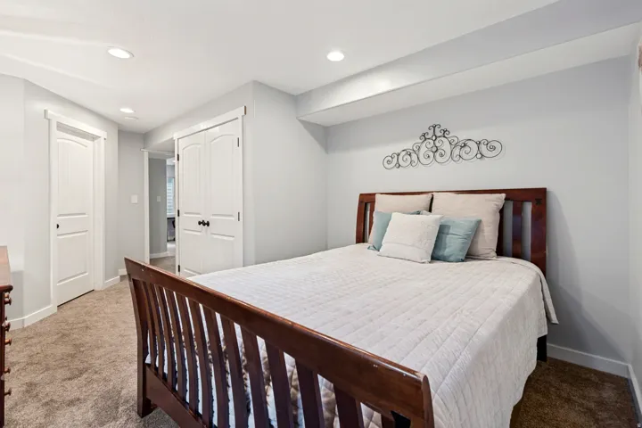 Recessed lighting, light gray wall paint, white trim, wood-finish headboard, and carpet flooring