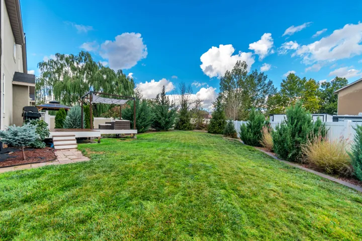 Expansive backyard featuring a lush lawn, multi-level deck, gazebo, pergola, and privacy fencing