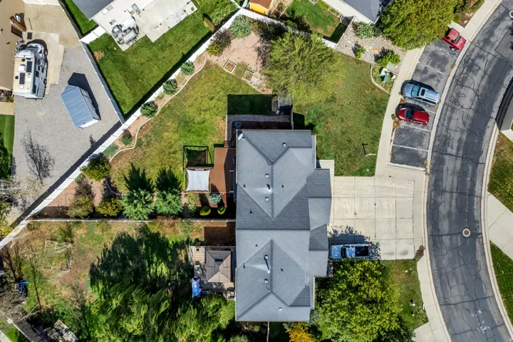 Gray shingle roof, expansive paved driveway, and mature landscaping