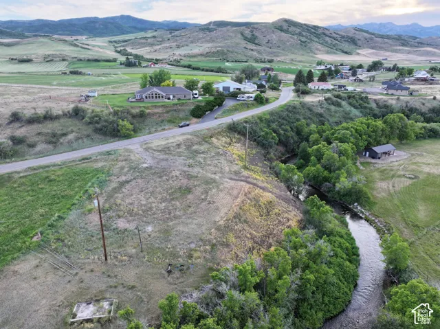 Property situated in a valley setting with surrounding hills, including a visible river, open land, and a paved road