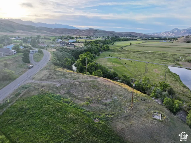 Expansive green landscape featuring a river, a body of water, and distant mountains